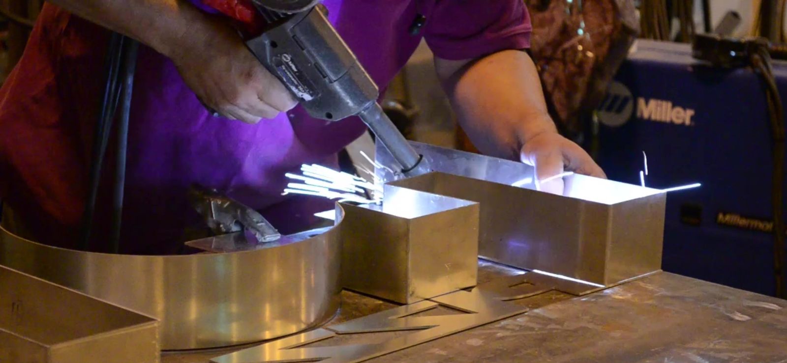 Female Fabricator Constructing Metal Sign Using Specialized Tools