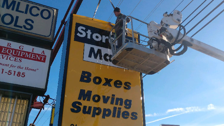 Sign Store employee on crane installing sign