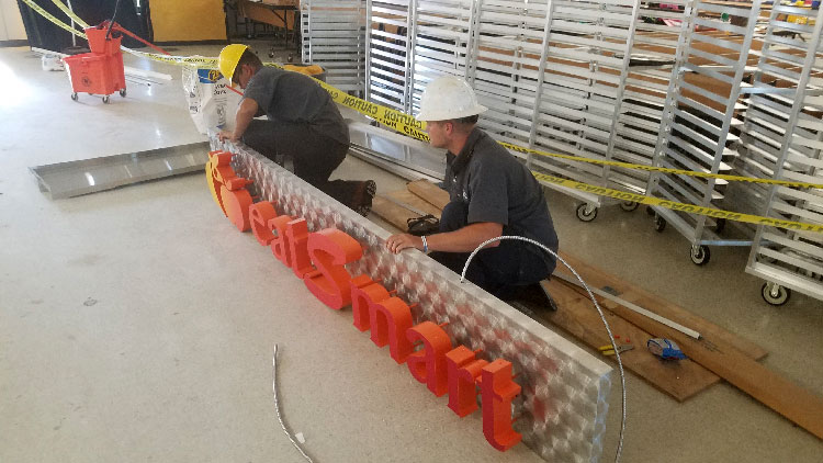 Sign Store employees wearing hard hats installing a sign