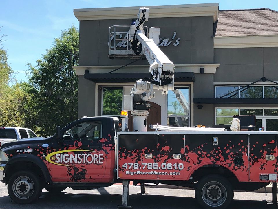 Sign Store employees wearing hard hats installing a sign